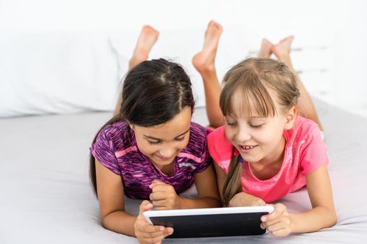 people, children, technology, friends and friendship concept - girls looking to tablet pc computers at home.