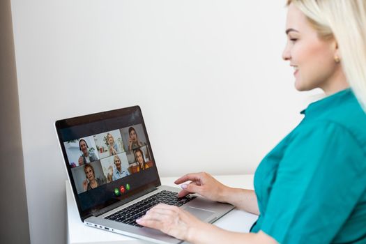 Woman having video chat with colleagues at table in office, closeup.