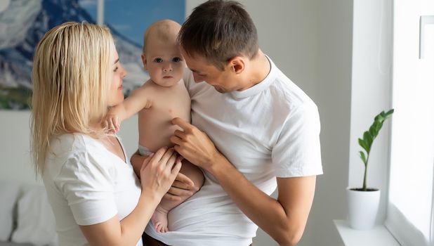 A Happy young family with baby in white bedroom.