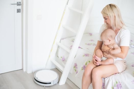 Little baby boy looks at the robotic vacuum cleaner at home