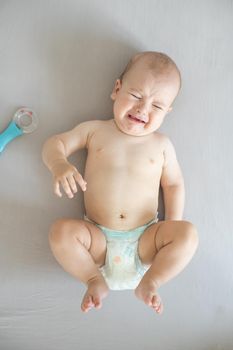 Portrait of crying baby on bed.