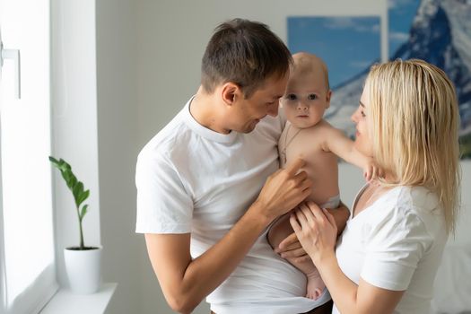 Portrait of happy young parents with baby at home.