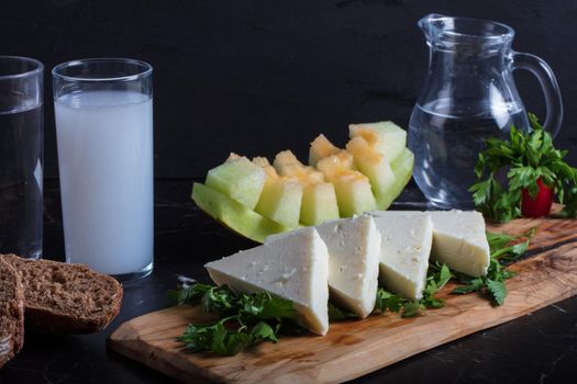 Turkish Raki with water on table with sliced melon and appetizer, traditional Turkish alcohol known as Raki, chill with friends at restaurant, dinner idea, eating and drinking concept, sitting view. High quality photo
