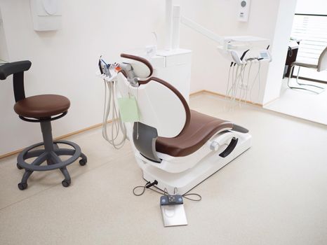 Modern dental office. Brown leather chair and other accessories used by dentists in white medic light. High quality photo