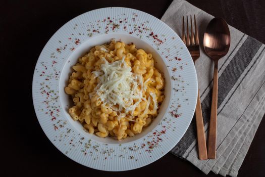 Mac and cheese, american style macaroni pasta with cheesy sauce on dark rustic table, top view. High quality photo