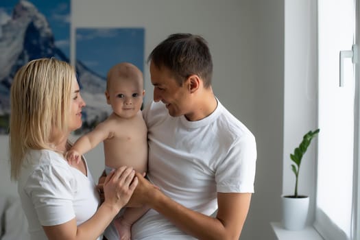 middle-aged parents with baby in white bedroom.