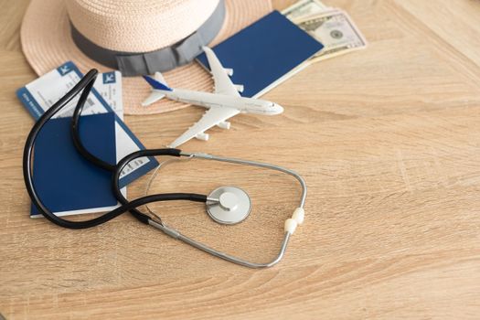 Travel and healthcare concept. Top view of passport, stethoscope and toy plane on wooden background with copy space