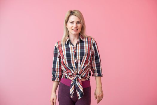 woman with long blonde hair standing isolated over pink background, posing.