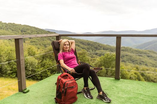 stylish traveler woman relaxing in mountains. hipster on top of mountain, resting. space for text. atmospheric moment. wanderlust and travel concept