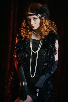 Portrait of vintage styled red haired woman dressed in Great Gatsby era flirting and posing on velours background. Roaring twenties, retro, party, fashion concept. High quality photo