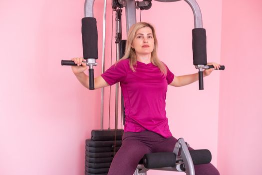 woman wearing pink and black professional sportswear pulling up at the gym. Strength and motivation concept