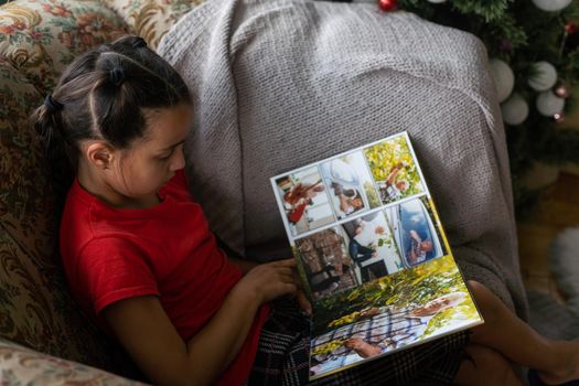 a little girl looking at a photo album in the living room.