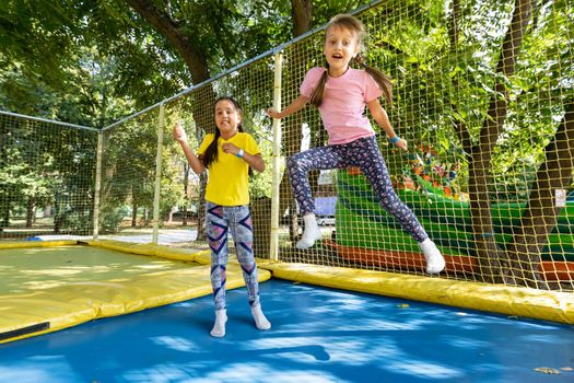 two young active girls doing exercises for squatting with trampoline.