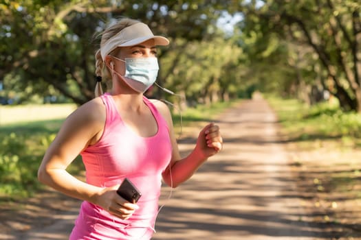 Pandemic coronavirus COVID-19 A woman in a meadow in a sports outfit wearing a protective mask in case of the spread of SARS-CoV-2 disease virus. Girl with a protective mask on her face