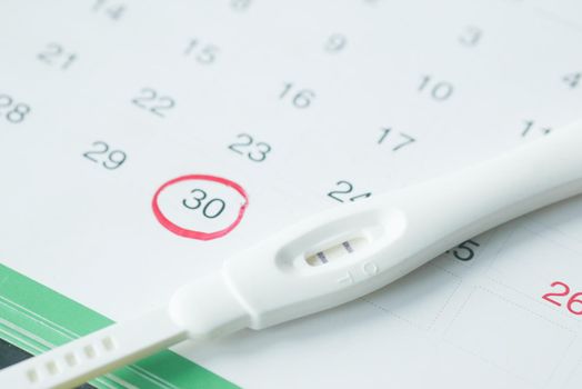 Pregnancy test kit on a calendar close up ,