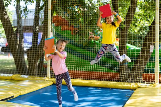 two girls with books jump on a trampoline