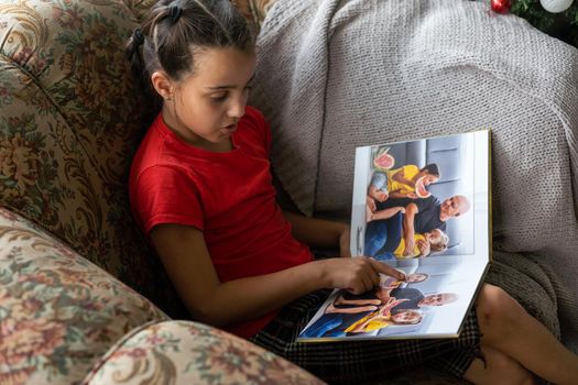 A Little Caucasian girl holding a photobook with her photographs in her hands.