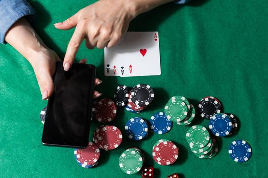 The concept of an online casino: playing cards, betting chips and a smartphone with a copy space in women's hands. Top view.