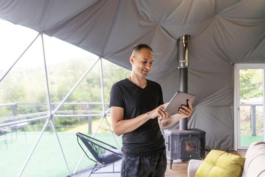 Man use application for smart home control on tablet. Interior of living room in the background