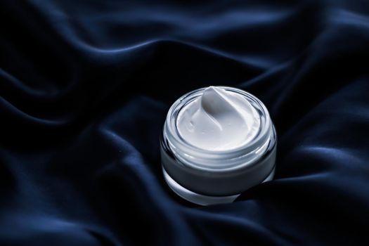 Beauty, anti-age cosmetics and skincare concept - Luxury face cream jar on a dark blue silk