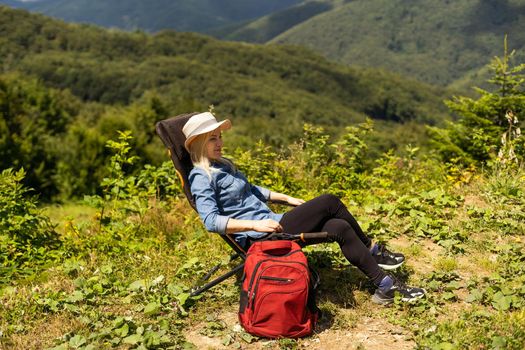 a woman rests after a hike in the mountains.