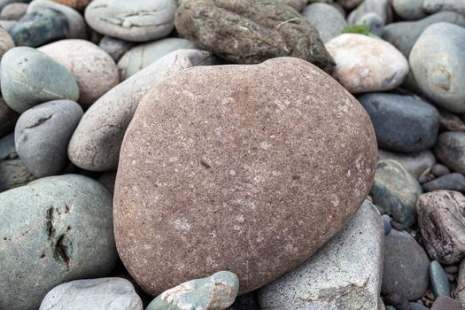 Large stones of different shapes on the riverbank close-up. there are a lot of small stones nearby.