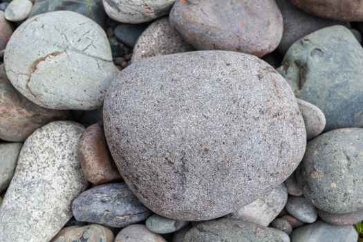 Large stones of different shapes on the riverbank close-up. there are a lot of small stones nearby.