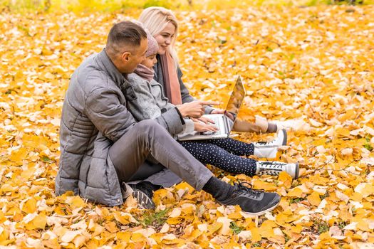 Online communication. Family using laptop and video calling , sitting on picnic blanket in garden