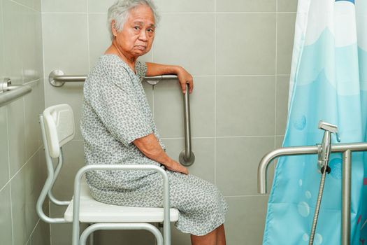 Asian elderly old woman patient use toilet support rail in bathroom, handrail safety grab bar, security in nursing hospital.