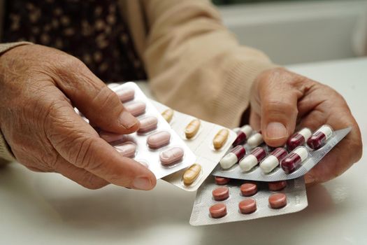 Asian elderly woman holding pill drug in hand, strong healthy medical concept.