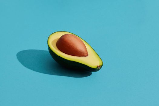 Food design. Colorful fruit pattern of fresh cutted avocado halves with pits inside on blue pastel background. Mock up, flat lay style.