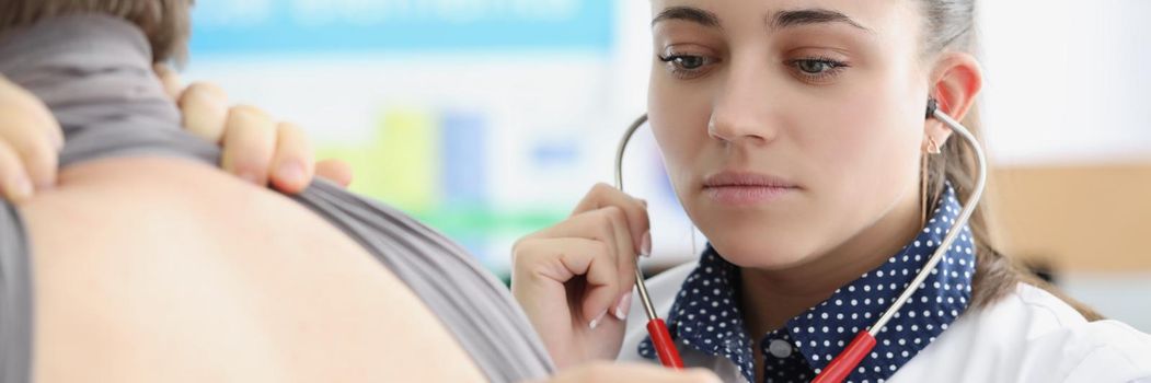 Woman pulmonologist listening to lungs of patient with stethoscope in clinic. Diagnostics and treatment of pneumonia concept