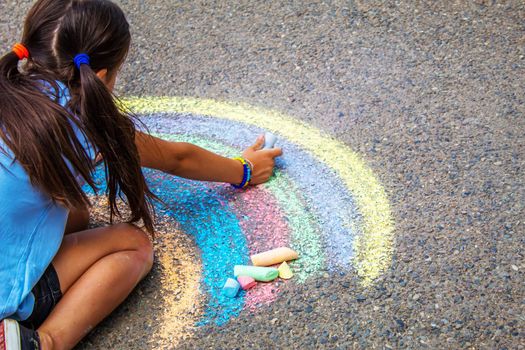 A child draws a rainbow on the asphalt. Selective focus. kid.