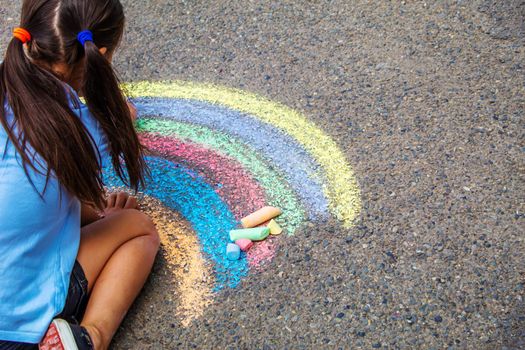 A child draws a rainbow on the asphalt. Selective focus. kid.