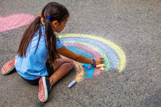 A child draws a rainbow on the asphalt. Selective focus. kid.