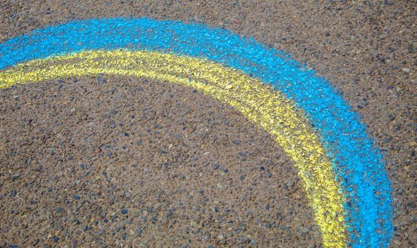 Children paint a rainbow on the asphalt. Selective focus. Kids.