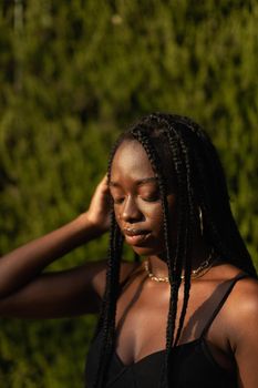 Portrait of a young black female removing her hair from her face whit her eyes closed during a sunset modeling session