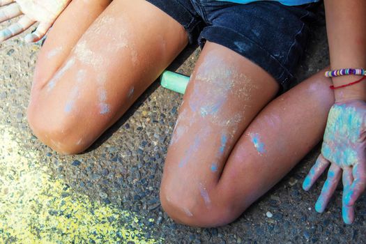 Children paint a rainbow on the asphalt. Selective focus. Kids.