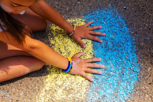 Children paint a rainbow on the asphalt. Selective focus. Kids.