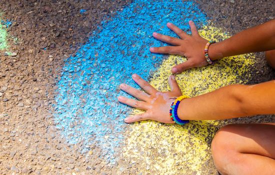 Children paint a rainbow on the asphalt. Selective focus. Kids.