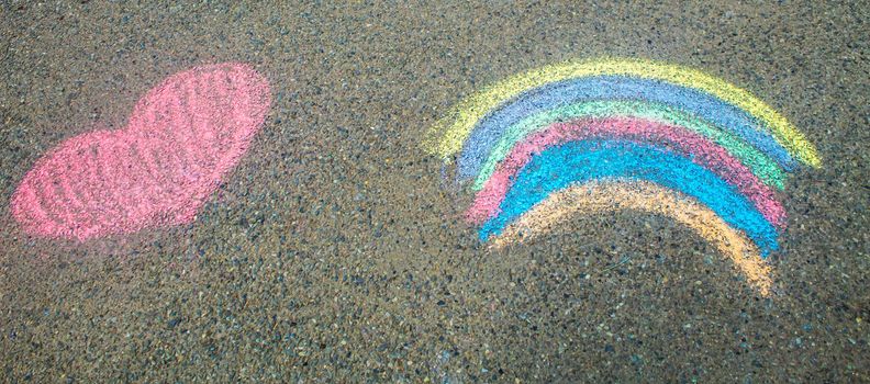 Children paint a rainbow on the asphalt. Selective focus. Kids.
