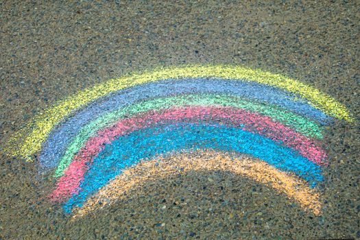 Children paint a rainbow on the asphalt. Selective focus. Kids.