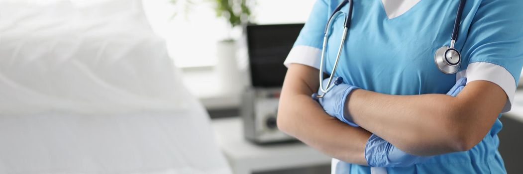 Woman doctor with crossed arms standing in hospital ward closeup. Severe patient care concept