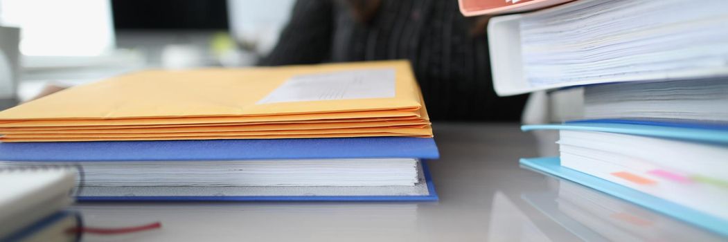 Woman sitting at table with many yellow envelopes and folders closeup. Paper work concept