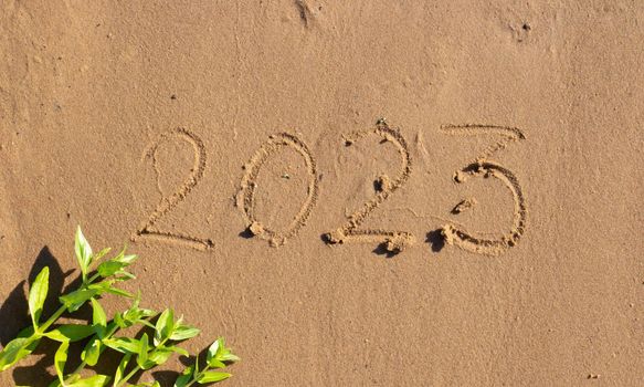 The numbers 2023 are written on the sand on the beach. The concept of the New Year. Happy New Year 2023 background. Travel during the Christmas holidays