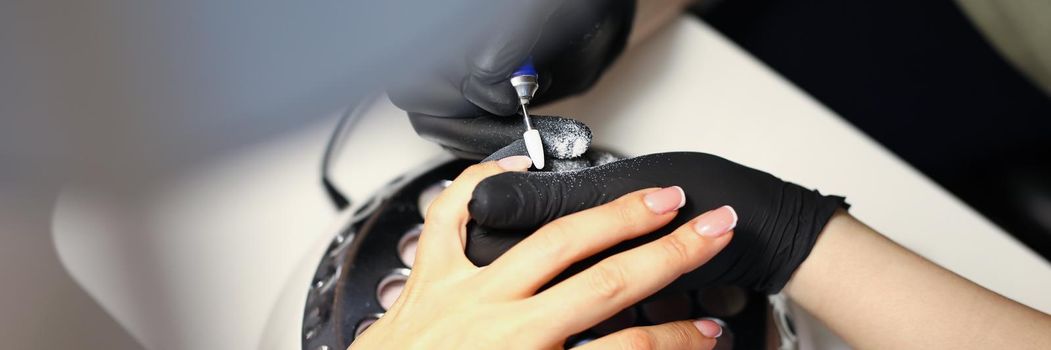 Woman master making manicure to client using special machine in beauty salon closeup. Beauty industry concept