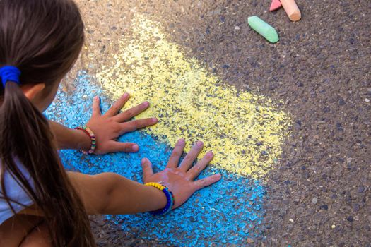 Children paint a rainbow on the asphalt. Selective focus. Kids.