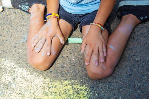 Children paint a rainbow on the asphalt. Selective focus. Kids.