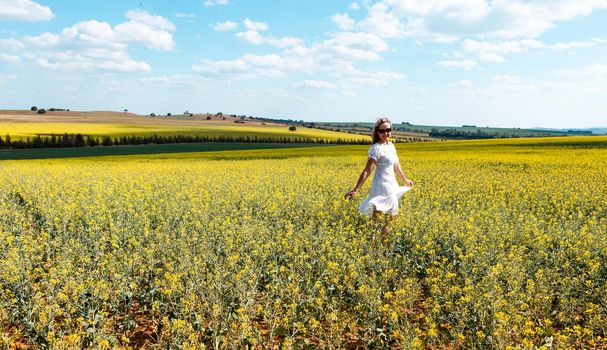 Woman frolicking in a field of flowers in teh spring time in rural country landscape