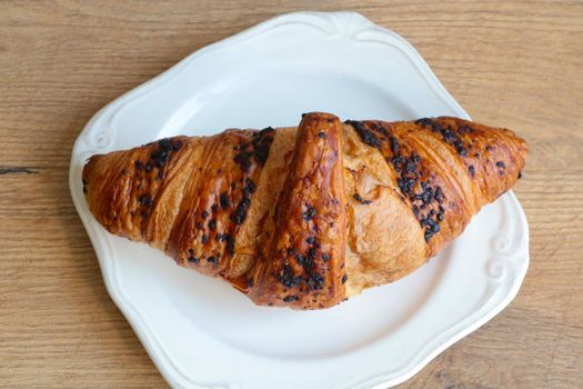 Delicious chocolodic croissant on a white plate in a cafe. Light and delicious breakfast